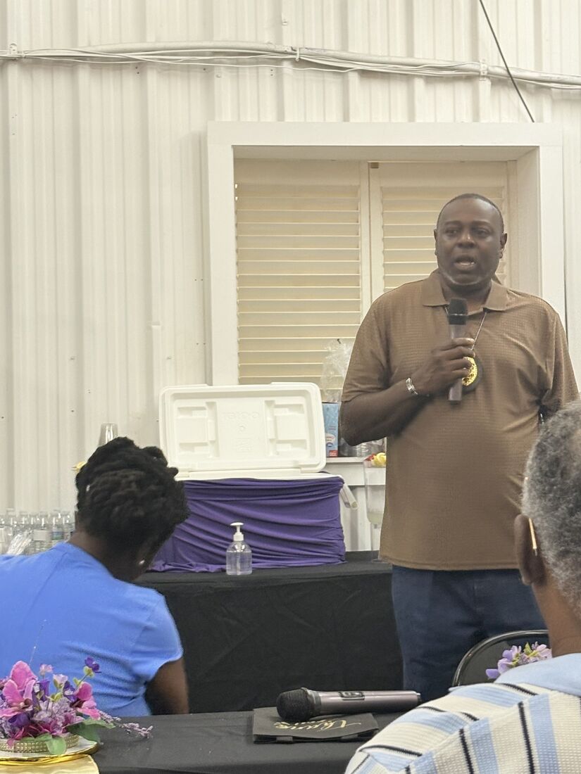 A man in a brown polo shirt speaking into a microphone at the launch event